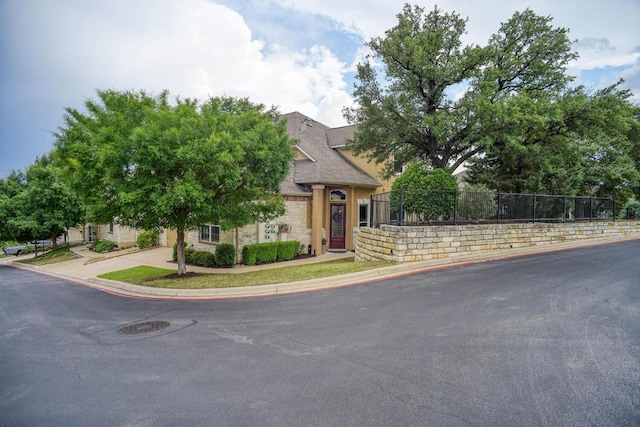 15208 Origins Ln, Austin, TX 78734 - obstructed view of property featuring stone siding, fence, and driveway