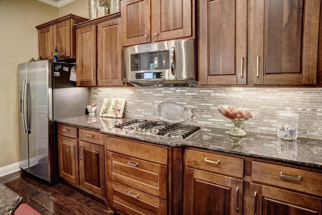 15208 Origins Ln, Austin, TX 78734 - kitchen with stainless steel appliances, decorative backsplash, dark stone counters, ornamental molding, and dark wood-type flooring