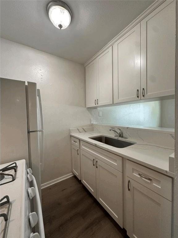 5207 Tahoe Trl Unit A, B, C, & D, Austin, TX 78745 - kitchen with white gas stove, dark wood-style floors, a sink, baseboards, and white cabinets
