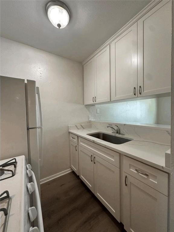 5207 Tahoe Trl Unit A, B, C, & D, Austin, TX 78745 - kitchen with white gas stove, dark wood-style floors, a sink, baseboards, and white cabinets