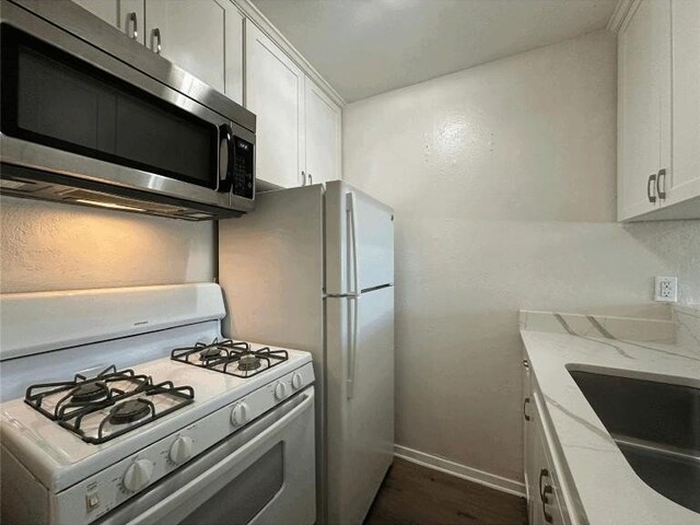 5207 Tahoe Trl Unit A, B, C, & D, Austin, TX 78745 - kitchen with white gas range oven, stainless steel microwave, white cabinetry, and light stone countertops