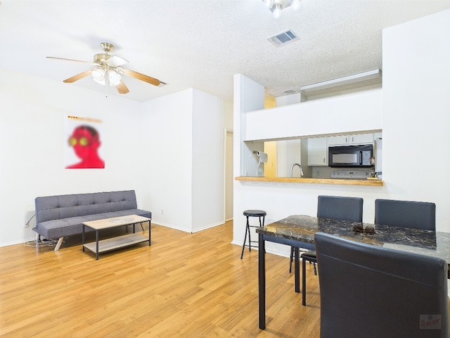 2905 Swisher St Unit 205, Austin, TX 78705 - dining space with wood finished floors, a ceiling fan, baseboards, and a textured ceiling
