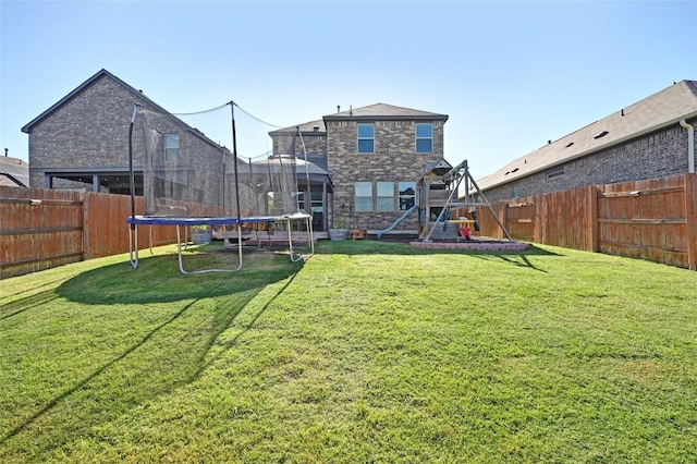 160 Thornless Cir, Buda, TX 78610 - back of house featuring a trampoline, a playground, and stone siding