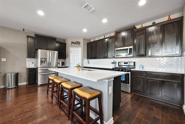 160 Thornless Cir, Buda, TX 78610 - kitchen featuring appliances with stainless steel finishes, a sink, a kitchen bar, dark wood finished floors, and light countertops