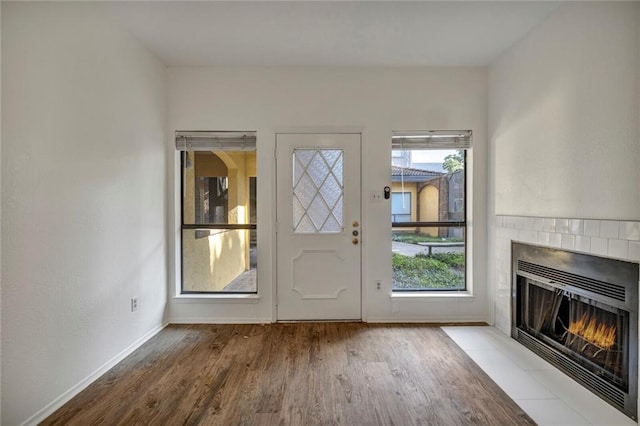 806 W 24th St Unit 114, Austin, TX 78705 - doorway to outside featuring wood finished floors, a tiled fireplace, and baseboards