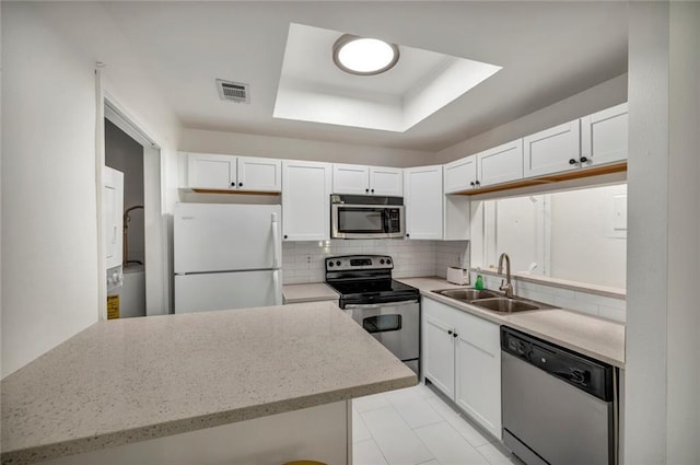 806 W 24th St Unit 114, Austin, TX 78705 - kitchen featuring stainless steel appliances, a sink, tasteful backsplash, a raised ceiling, and white cabinetry