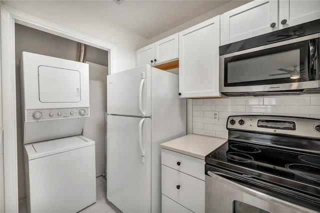 806 W 24th St Unit 114, Austin, TX 78705 - kitchen with stainless steel appliances, stacked washing machine and dryer, white cabinetry, light countertops, and decorative backsplash