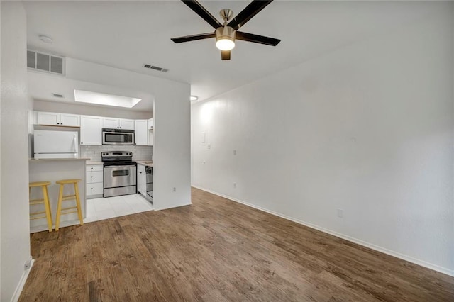 806 W 24th St Unit 114, Austin, TX 78705 - unfurnished living room with light wood finished floors, a ceiling fan, and baseboards