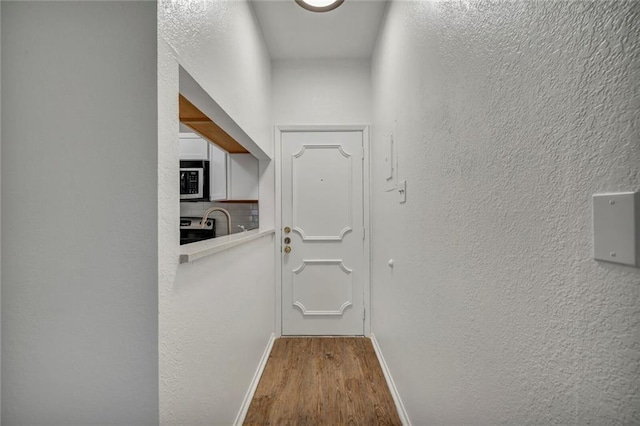 806 W 24th St Unit 114, Austin, TX 78705 - doorway featuring wood finished floors, baseboards, and a textured wall