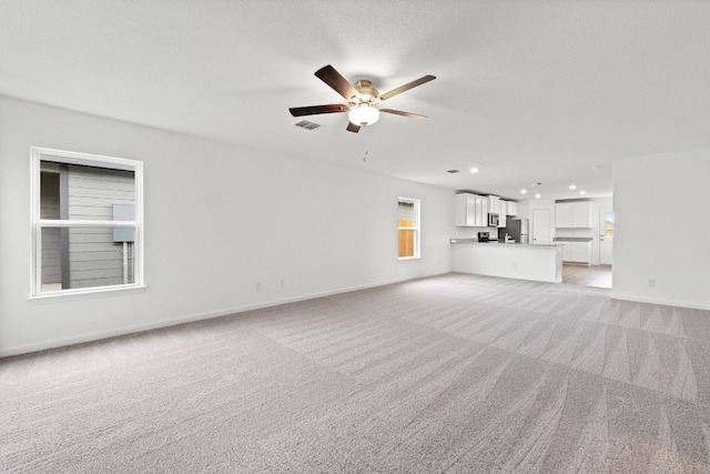 unfurnished living room with light colored carpet, a ceiling fan, baseboards, and recessed lighting