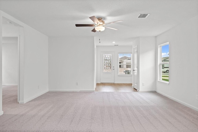 empty room featuring light colored carpet, ceiling fan, and baseboards