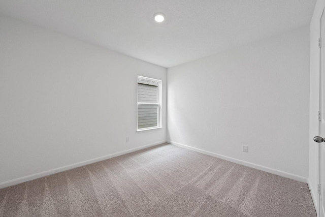 carpeted spare room featuring baseboards