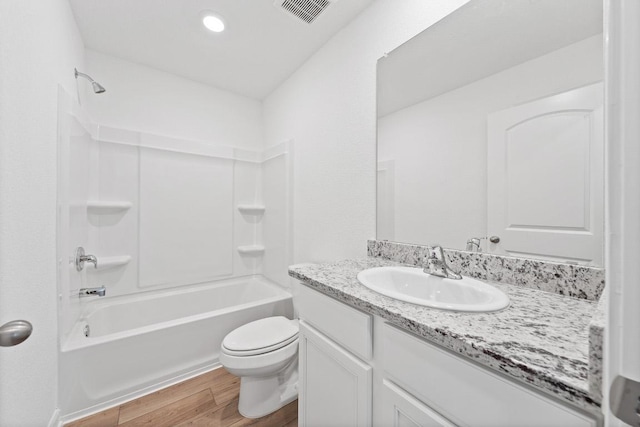 bathroom featuring wood finished floors, toilet, vanity, and bathtub / shower combination