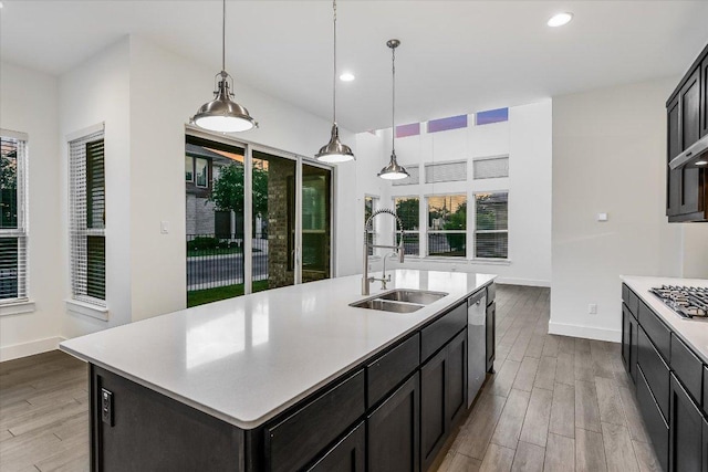 kitchen featuring a sink, stainless steel appliances, wood finished floors, light countertops, and recessed lighting
