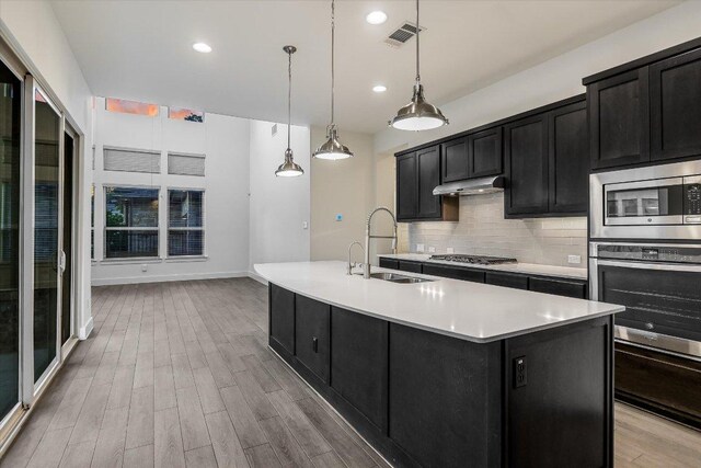 301 Jeffrey David Ln W, Austin, TX 78717 - kitchen with dark cabinetry, a sink, appliances with stainless steel finishes, light countertops, and tasteful backsplash