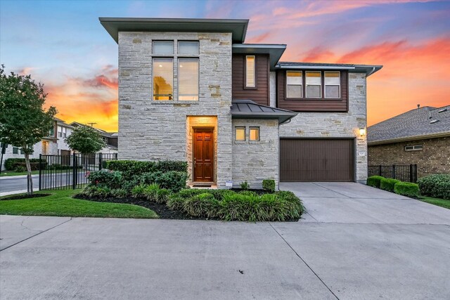 301 Jeffrey David Ln W, Austin, TX 78717 - contemporary house with stone siding, an attached garage, a standing seam roof, concrete driveway, and metal roof
