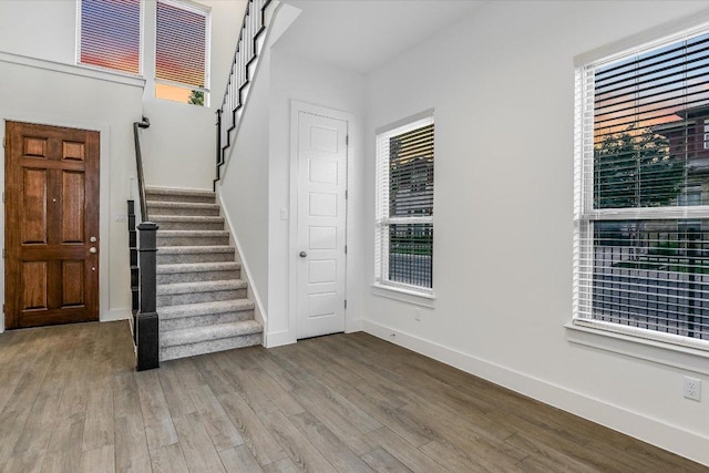 foyer entrance featuring wood finished floors, stairway, and baseboards