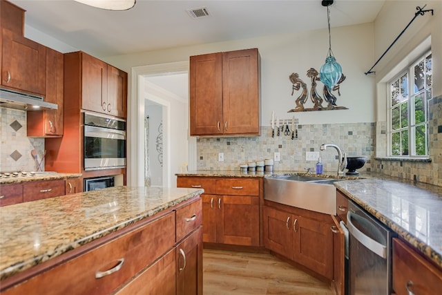 108 Tumbleweed Trl, Austin, TX 78733 - kitchen with appliances with stainless steel finishes, a sink, under cabinet range hood, light wood finished floors, and light stone counters