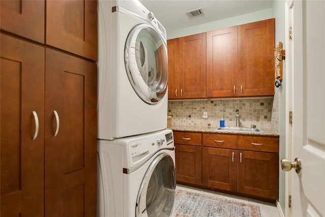 108 Tumbleweed Trl, Austin, TX 78733 - laundry area featuring stacked washer / drying machine, cabinet space, and light tile patterned floors