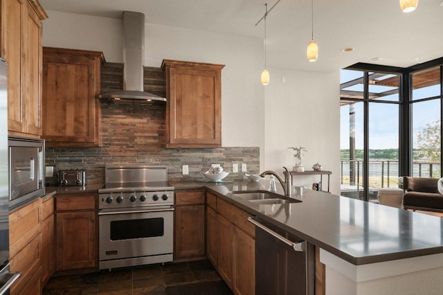 kitchen featuring appliances with stainless steel finishes, wall chimney range hood, dark countertops, a sink, and expansive windows
