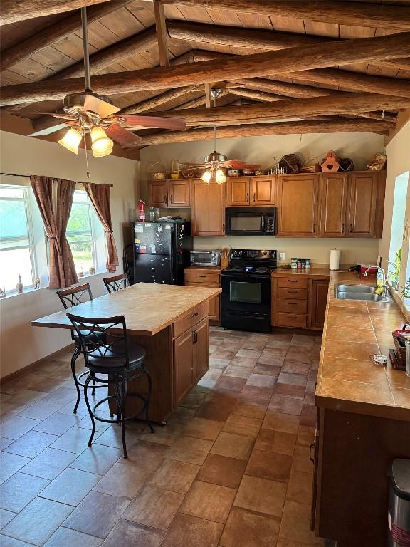 kitchen with black appliances, a sink, wooden ceiling, a breakfast bar area, and ceiling fan