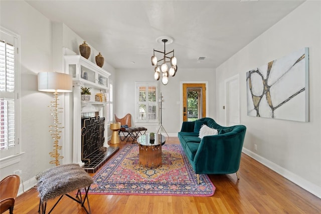 2106 Kenwood Ave, Austin, TX 78704 - living room with wood finished floors, a fireplace with raised hearth, baseboards, and a chandelier