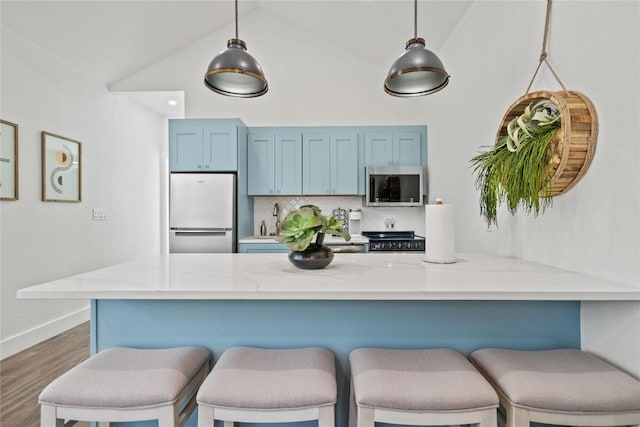 2106 Kenwood Ave, Austin, TX 78704 - kitchen with appliances with stainless steel finishes, blue cabinets, backsplash, light stone counters, and a breakfast bar