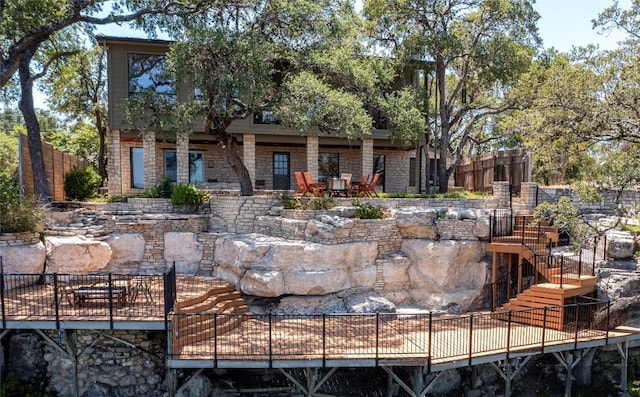 back of property featuring stairway, a wooden deck, fence, and stone siding