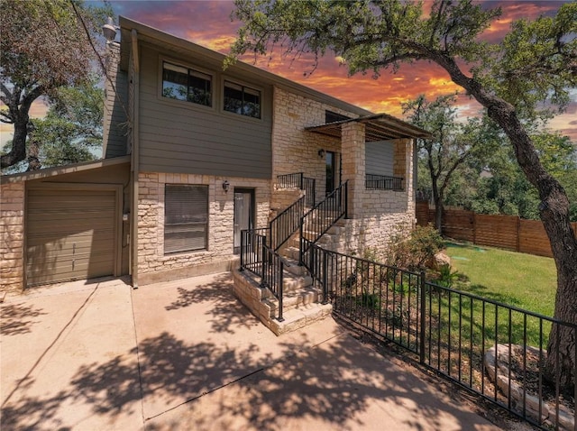 tri-level home featuring stone siding, stairs, and driveway