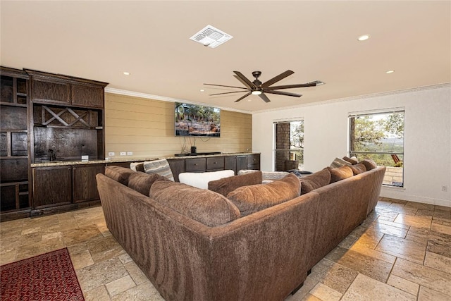 living room with stone tile flooring, recessed lighting, ornamental molding, a ceiling fan, and baseboards