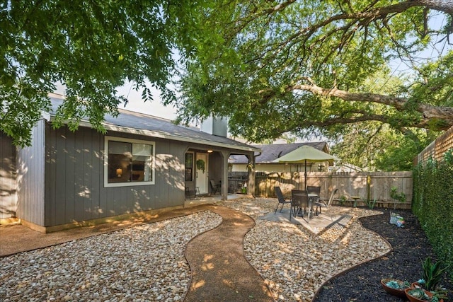 rear view of house with a fenced backyard and a patio