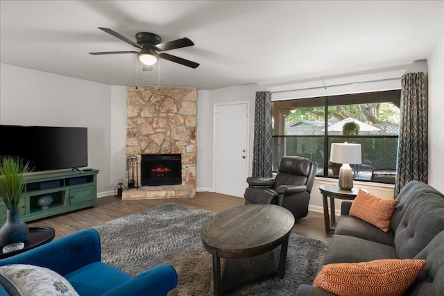 living area with ceiling fan, wood finished floors, a fireplace, and baseboards