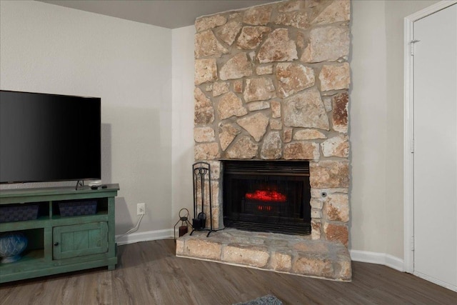 detailed view of wood finished floors, baseboards, and a fireplace