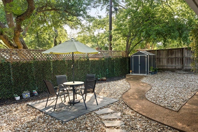 view of patio with a storage unit, a fenced backyard, and an outbuilding