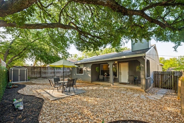 rear view of property featuring a storage shed, a fenced backyard, a patio, and an outdoor structure