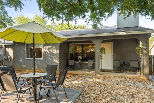 back of property featuring a patio area, roof with shingles, and outdoor dining space