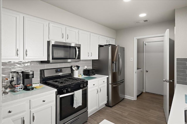 kitchen featuring stainless steel appliances, white cabinetry, light countertops, and tasteful backsplash