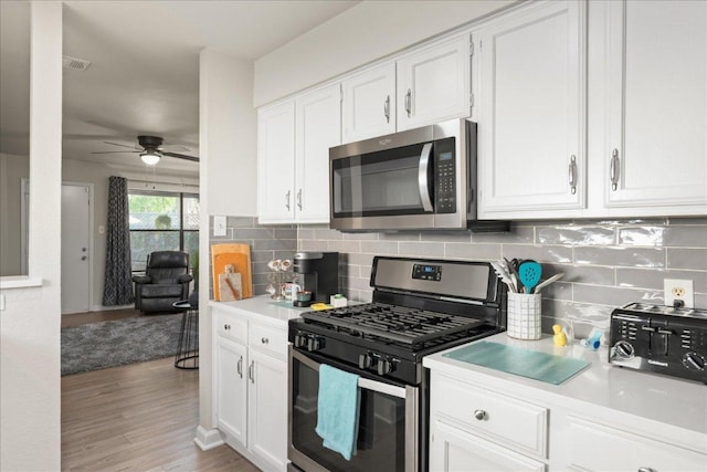kitchen featuring stainless steel appliances, a ceiling fan, light countertops, white cabinets, and tasteful backsplash