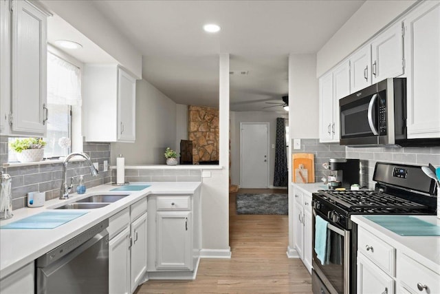 kitchen with stainless steel appliances, a sink, light wood-style flooring, white cabinetry, and light countertops