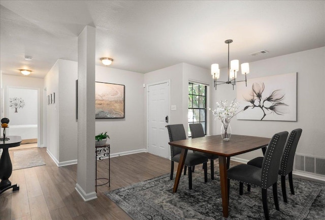 dining area featuring a chandelier, wood finished floors, and baseboards