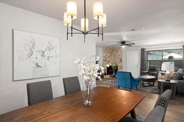 dining area with wood finished floors, a chandelier, and ceiling fan