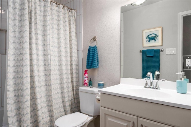 bathroom with a textured wall, toilet, a shower with shower curtain, and vanity