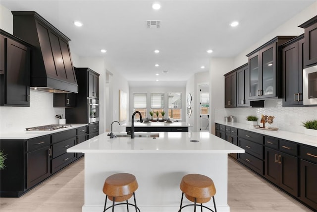 232 San Xavier St, Georgetown, TX 78633 - kitchen featuring stainless steel appliances, an island with sink, light wood-style flooring, backsplash, and a breakfast bar area