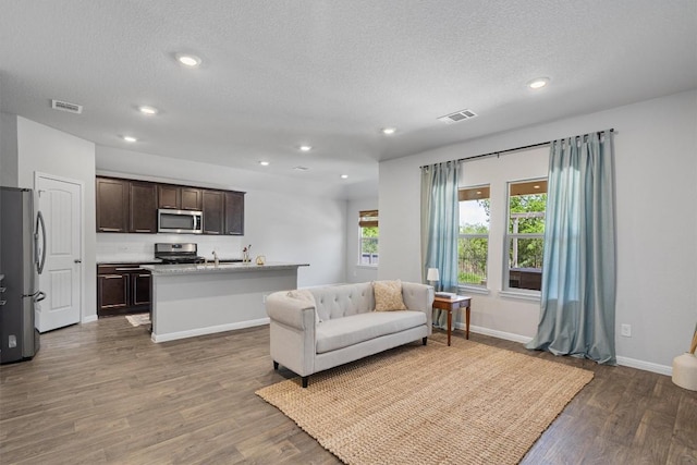 13921 Allan Shivers St, Manor, TX 78653 - living room featuring dark wood-style flooring, baseboards, a textured ceiling, and recessed lighting