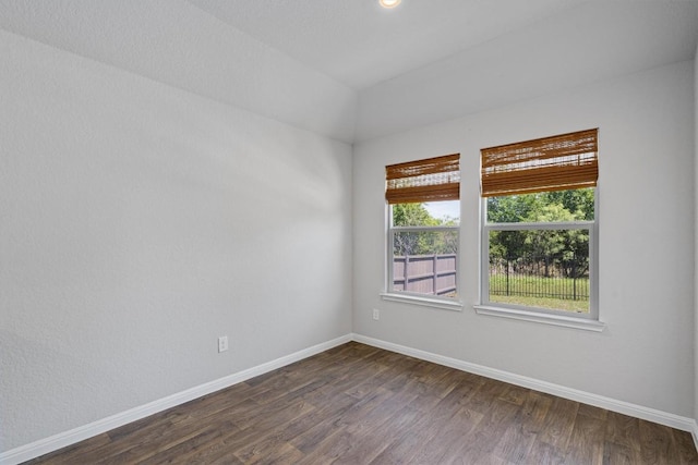 spare room with baseboards and dark wood-type flooring