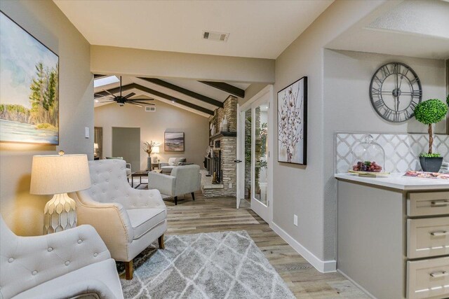 living area featuring light wood-style flooring, baseboards, a ceiling fan, and a fireplace