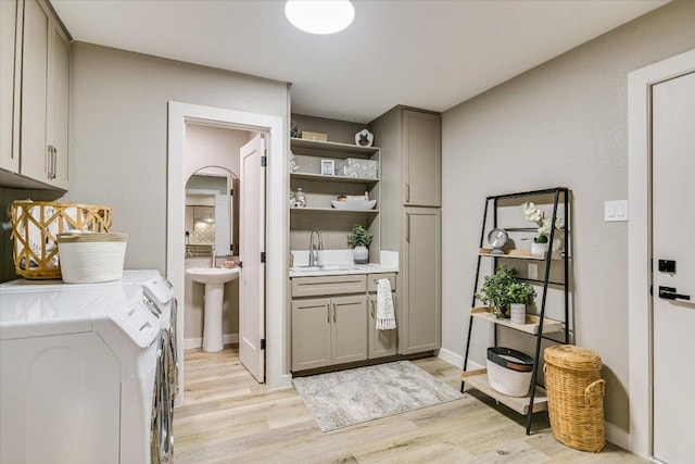 bar featuring a sink, independent washer and dryer, light wood finished floors, and arched walkways