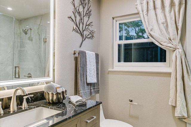 bathroom featuring a stall shower, vanity, a textured wall, and toilet