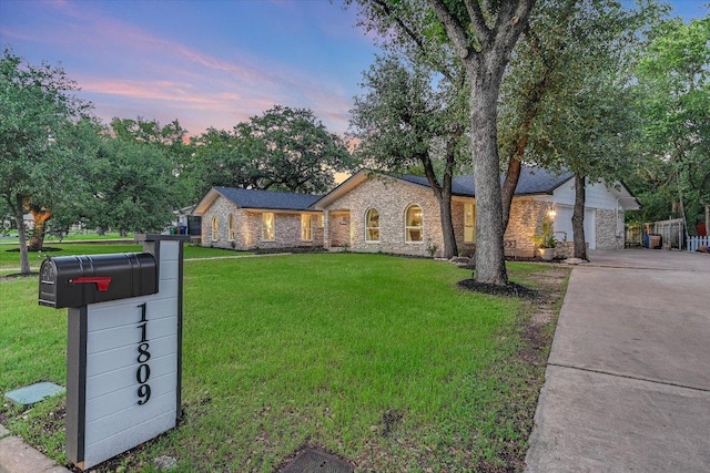 ranch-style home with stone siding, driveway, and a yard