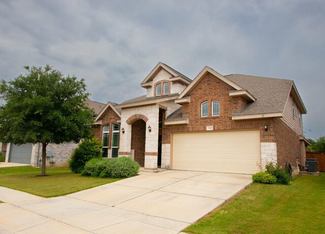 3119 Brand Iron Dr, San Marcos, TX 78666 - view of front of home featuring stone siding, central air condition unit, an attached garage, driveway, and a front lawn